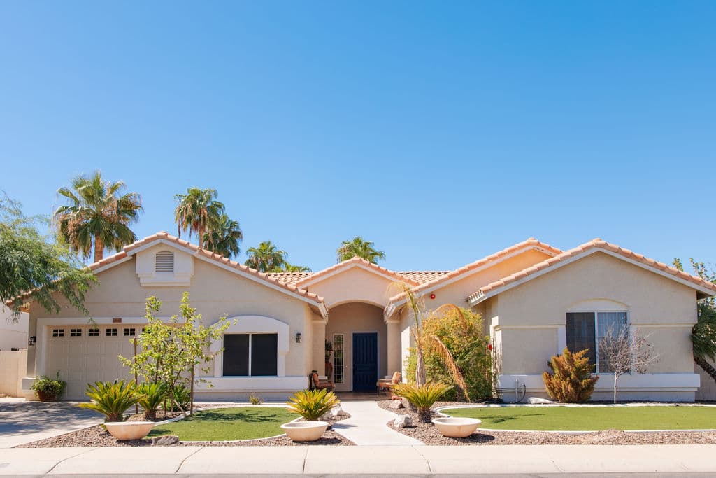 The Liora home seen from the street, with desert landscaping, palms and a wide front lawn under a clear blue sky.