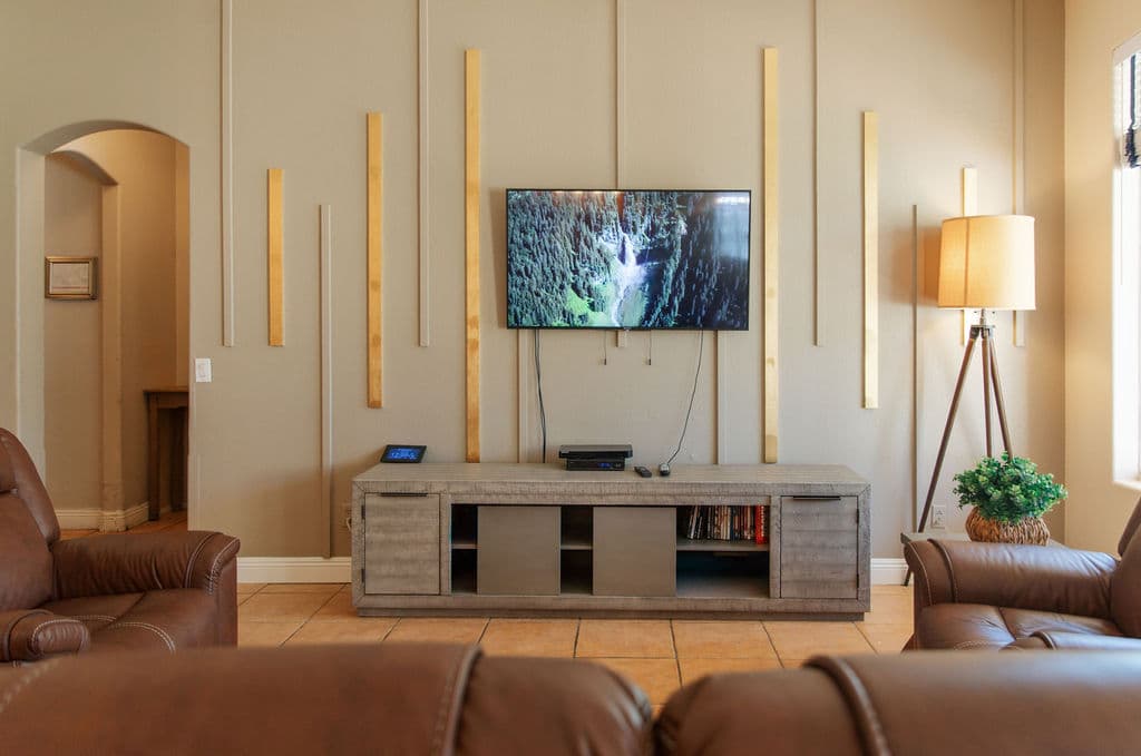 The living room's feature wall with slim timber accents, a media console and a tripod floor lamp.